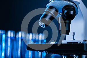 Close up of laboratory microscope with set of test tubes with blue liquid