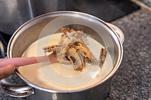 Close-up of a ladle taking out cod to remove the salt with milk