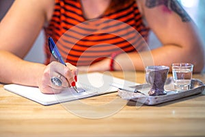 Close up of lady`s hand writing in notepad in coofee bar.