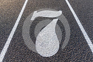 Close up lane number seven, 7, on a new black running track with white lane lines and other markings