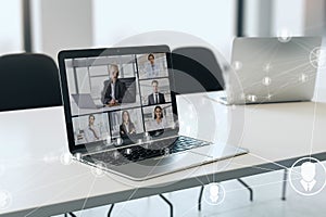 Close up of laptop computer on desk with glowing video conference hologram and polygonal connections on blurry office background.