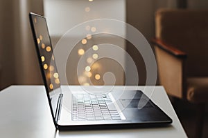 Close up of laptop keyboard with blank screen on a table by blurry bokeh lights background in the house or office modern