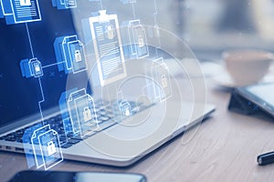 Close up of laptop and other items on wooden desk with creative digital chain of documents on blurry background. Security, data,