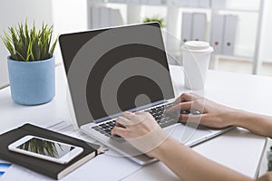 Close up of laptop screen with woman's hands on keyboard