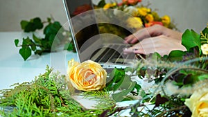Close-up of laptop on which hands of female flower designer prin