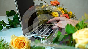 Close-up of laptop on which hands of female flower designer prin