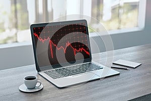 Close up of laptop on wooden desktop with coffee cup falling red business graph grid on window with city view office background.