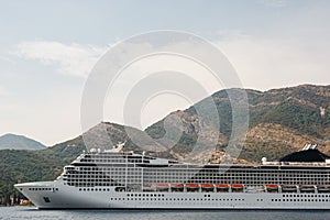 A close-up of a large cruise liner in the Kotor Bay of Montenegro, against the backdrop of a mountain.