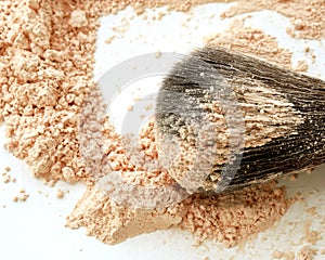 Close-up of large makeup brush with loose cosmetic powder on white background. Side view.