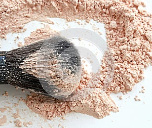 Close-up of large makeup brush with loose cosmetic powder on white background. Side view.