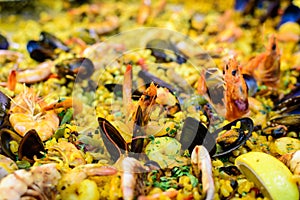 Close up of large portion of traditional Spanish paella dish freshly being cooked with seafood and pasta in a  frying pan at a str