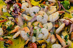 Close up of large portion of traditional Spanish paella dish freshly being cooked with seafood and pasta in a frying pan at a str