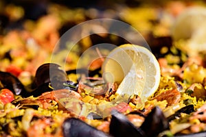 Close up of large portion of traditional Spanish paella dish freshly being cooked with seafood and rice in a frying pan at a stree