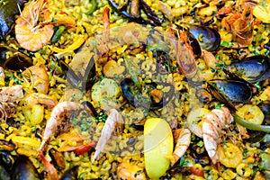 Close up of large portion of traditional Spanish paella dish freshly being cooked with seafood and rice in a frying pan at a