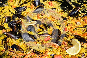 Close up of large portion of traditional Spanish paella dish freshly being cooked with seafood and rice in a frying pan at a stree
