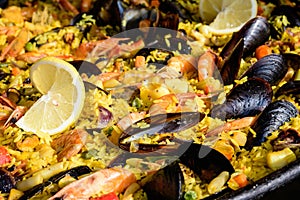 Close up of large portion of traditional Spanish paella dish freshly being cooked with seafood and rice in a frying pan at a