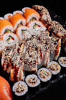 Close up of a large set of various sushi rolls with various fresh fish and vegetable fillings.