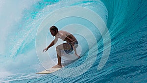 CLOSE UP: Large tube wave curls behind fearless sportsman surfing in Tahiti.