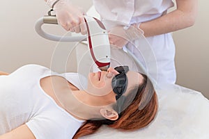 Close-up of laser hair removal on a woman& x27;s face. The doctor removes unwanted hair from the patient above the lip with