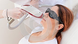 Close-up of laser hair removal on a woman& x27;s face. The doctor removes unwanted hair from the patient above the lip with