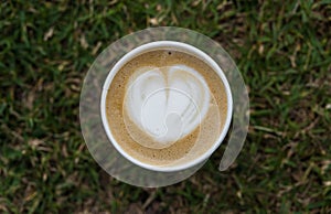 Close up of latte cappuccino coffee cup with frothed milk in heart shape.