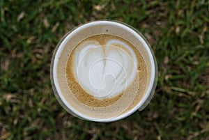 Close up of latte cappuccino coffee cup with frothed milk in heart shape.