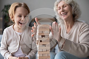 Close up laughing mature woman and granddaughter building wooden tower