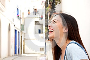 Close up laughing young woman standing on city street
