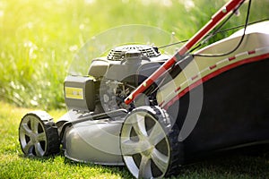Close up of lawn mower on the grass, ready for cutting the grass in the garden, gardening concept, copy space