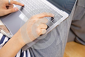 Close up and lay flat view of asian woman working at home with laptop typing hands on wooden floor shows concept of working from