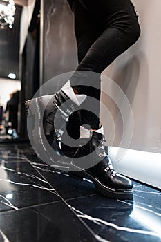 Close-up of leather fashionable autumn-winter warm black-white boots on female legs. New seasonal collection of women`s shoes