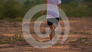 Close up leg of boy running on ground on light of sunset, kids jogging on rural countryside for good heath