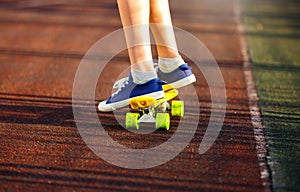 Close up legs in blue sneakers riding on yellow skateboard in motion. Active urban lifestyle of youth, training, hobby, activity