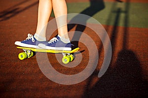 Close up legs in blue sneakers riding on yellow skateboard in motion. Active urban lifestyle of youth, training, hobby,  activity