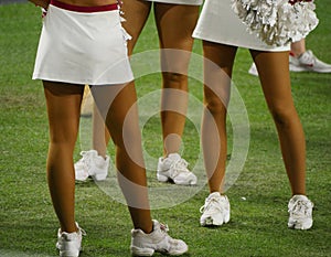 Close up of legs of cheerleaders standing in a football field sideline