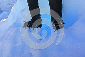 Feet in hiking boots with crampons on glaciar trail. Outdoors activity, trekking by glaciers and snow mountains