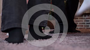 Close-up legs of a family circling a round dance for Christmas at the Christmas tree. Grandparents and granddaughters