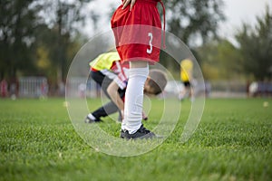 Close up of the legs and feet of a child soccer player in black football boots