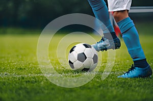 Close up of legs and feet of football player in blue socks and shoes running and dribbling with the ball