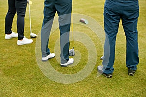 Close Up Of Legs Of Golfers Holding Clubs On Golf Tee
