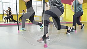 Close up legs of group of women doing pilates exercises squats in fitness studio