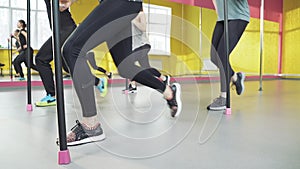 Close up legs of group of women doing pilates exercises squats in fitness studio.