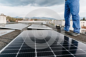 Close-up on the legs of a man standing by solar panels on the roof of a house Alternative energy. Cover photo