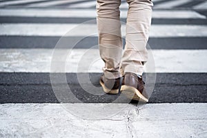 Close up legs of man walking cross street in city