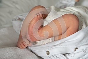 Close up on legs of newborn baby lying on the bed at home - unknown caucasian infant waiting to get dressed or undressed -growing