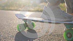 Close up legs riding on skateboard in motion of asphalt at sunset. Youth leisure concept. Active outdoor sport for kids.