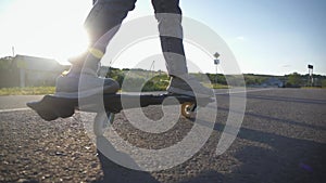 Close up legs riding on skateboard in motion of asphalt at sunset. Youth leisure concept. Active outdoor sport for kids.