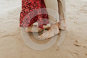 Close up of legs on a sand. Couple in love standing on a sandy beach. Holiday concept.