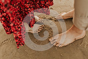 Close up of legs on a sand. Couple in love standing on a sandy beach. Holiday concept.