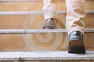 Close up legs shoes of young business man One person walking stepping going up the stairs in modern city,